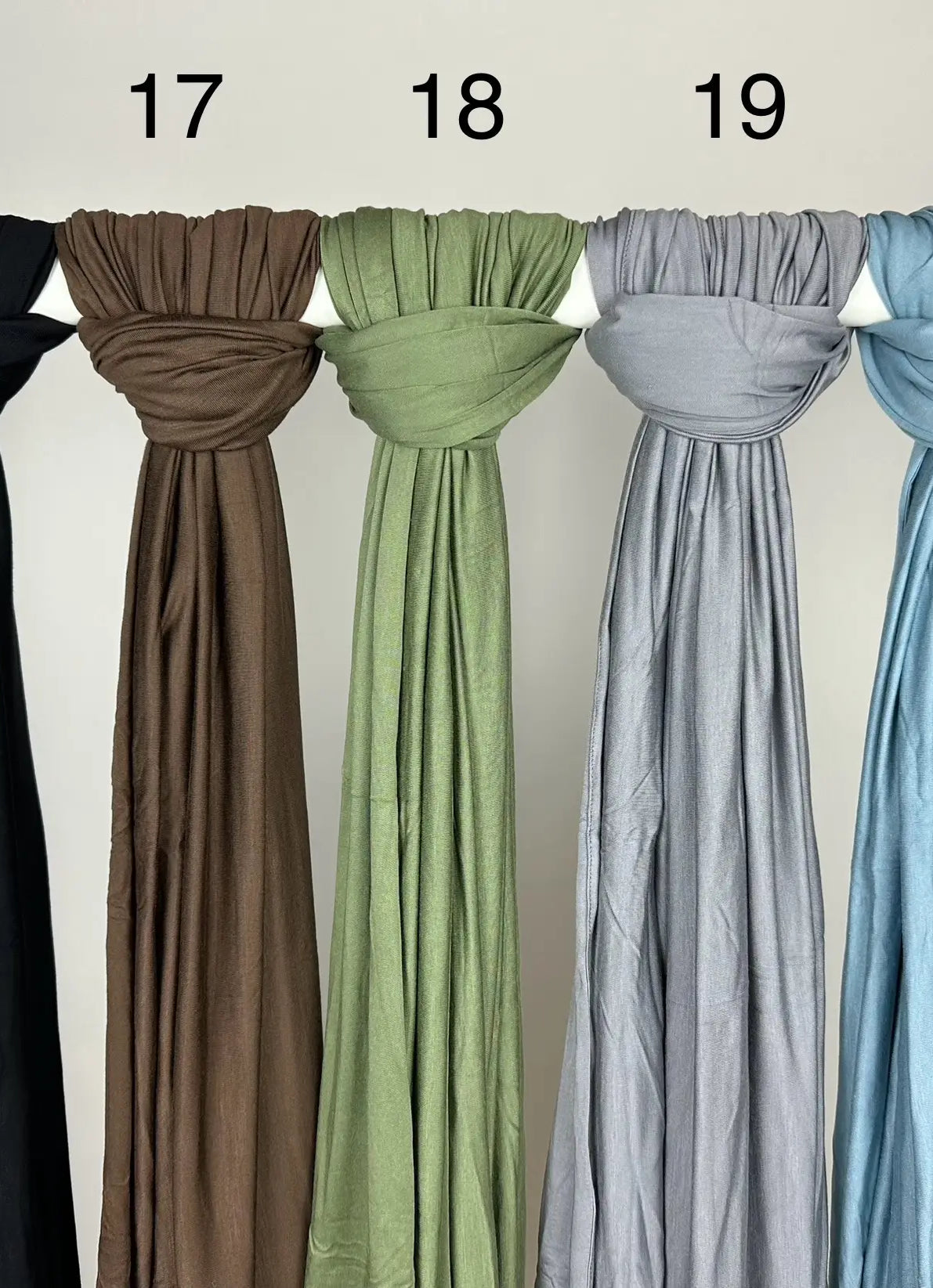 Mehrfarbige Premium-Jersey-Hijabs für Abaya-Modest-Styles hängen weich fallend an einer Stange, Vorderansicht