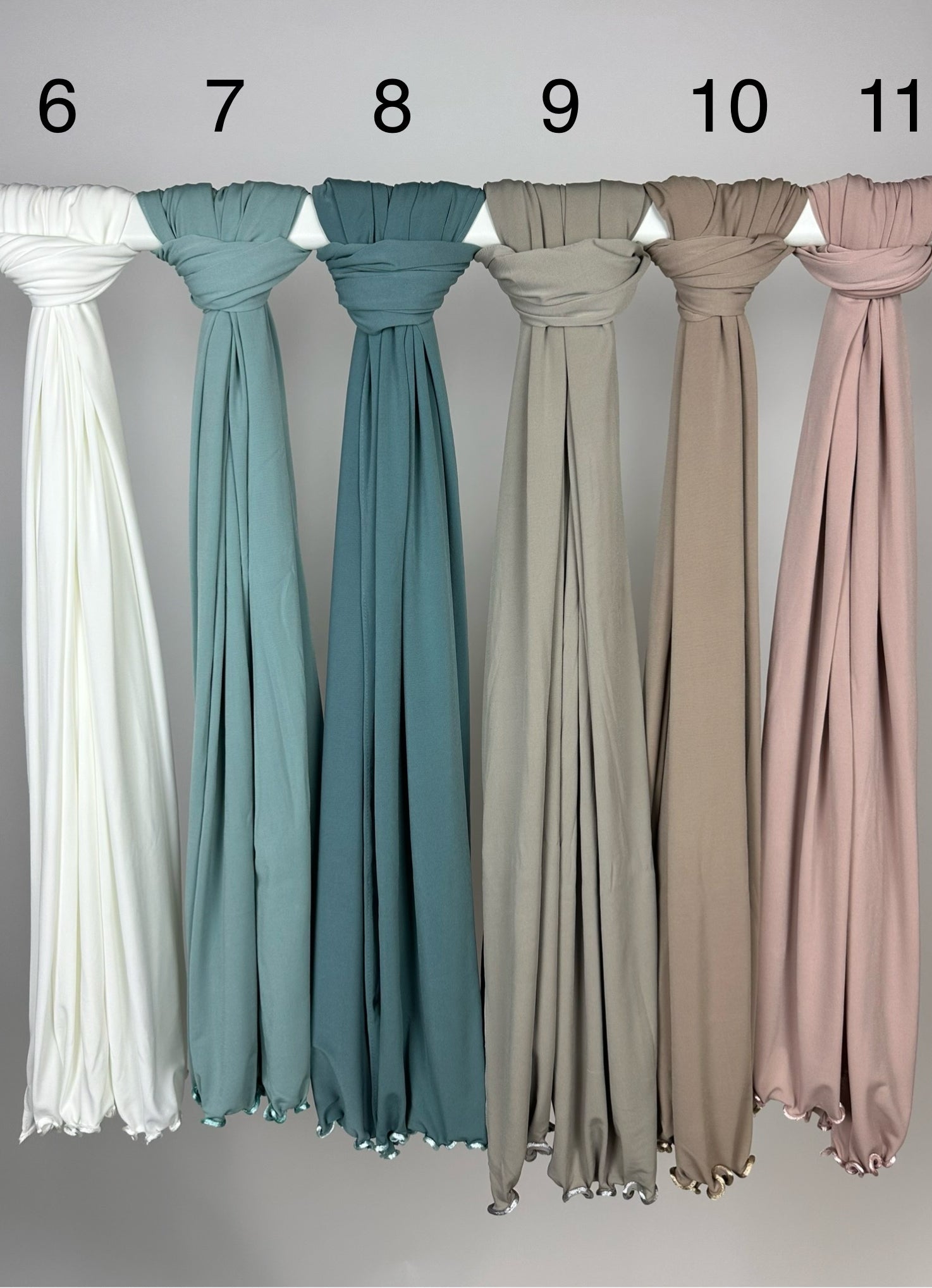 Mehrfarbige Crinkle-Hijabs aus leichtem Stoff mit gewelltem Saum, nummeriert und hängend an Stange, Frontansicht