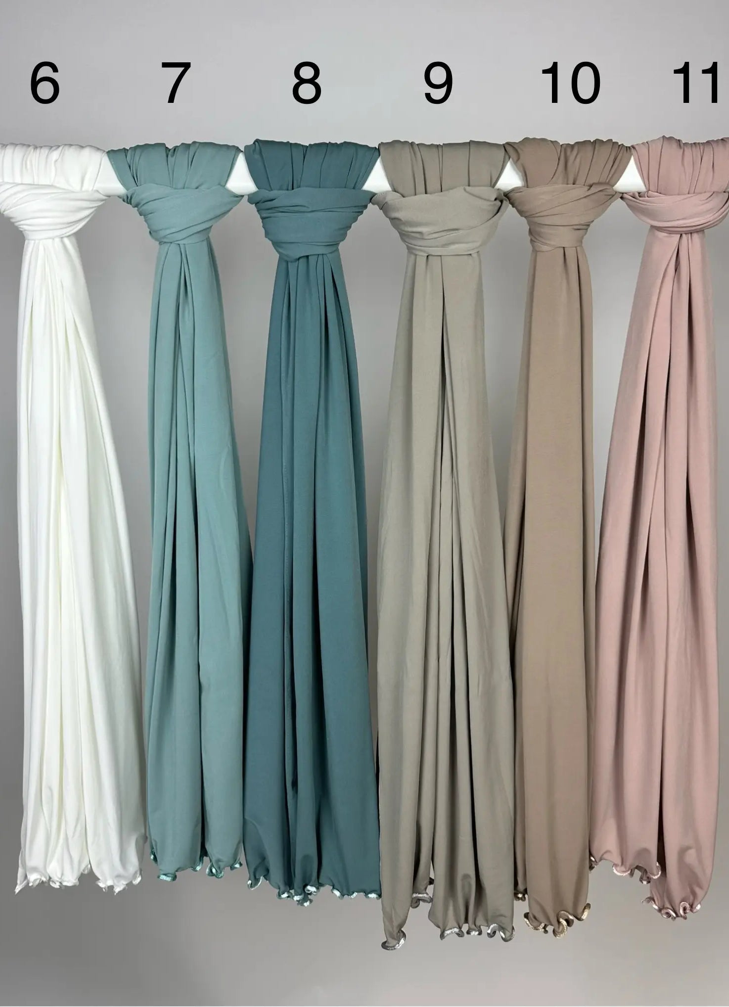 Mehrfarbige Crinkle-Hijabs aus leichtem Stoff mit gewelltem Saum, nummeriert und hängend an Stange, Frontansicht