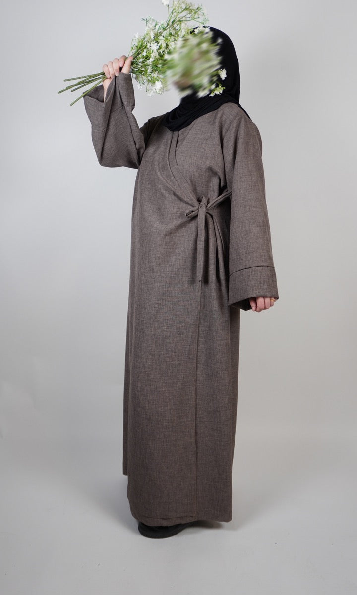Dunkelblaue Wickelabaya in Leinenoptik mit kleiner Schleife, seitliche Ansicht des Modells, Modest-Fashion Abaya.