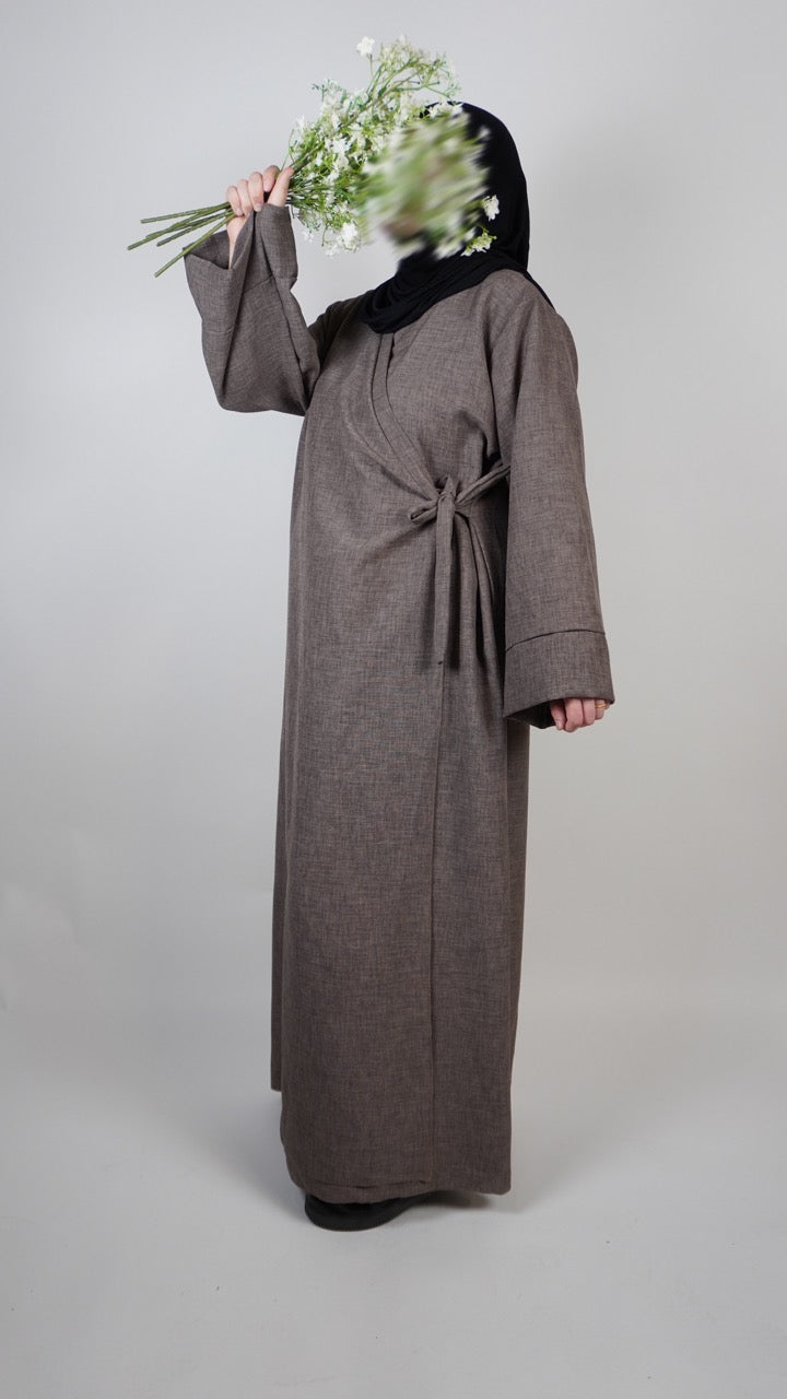 Dunkelblaue Wickelabaya in Leinenoptik mit kleiner Schleife, seitliche Ansicht des Modells, Modest-Fashion Abaya.