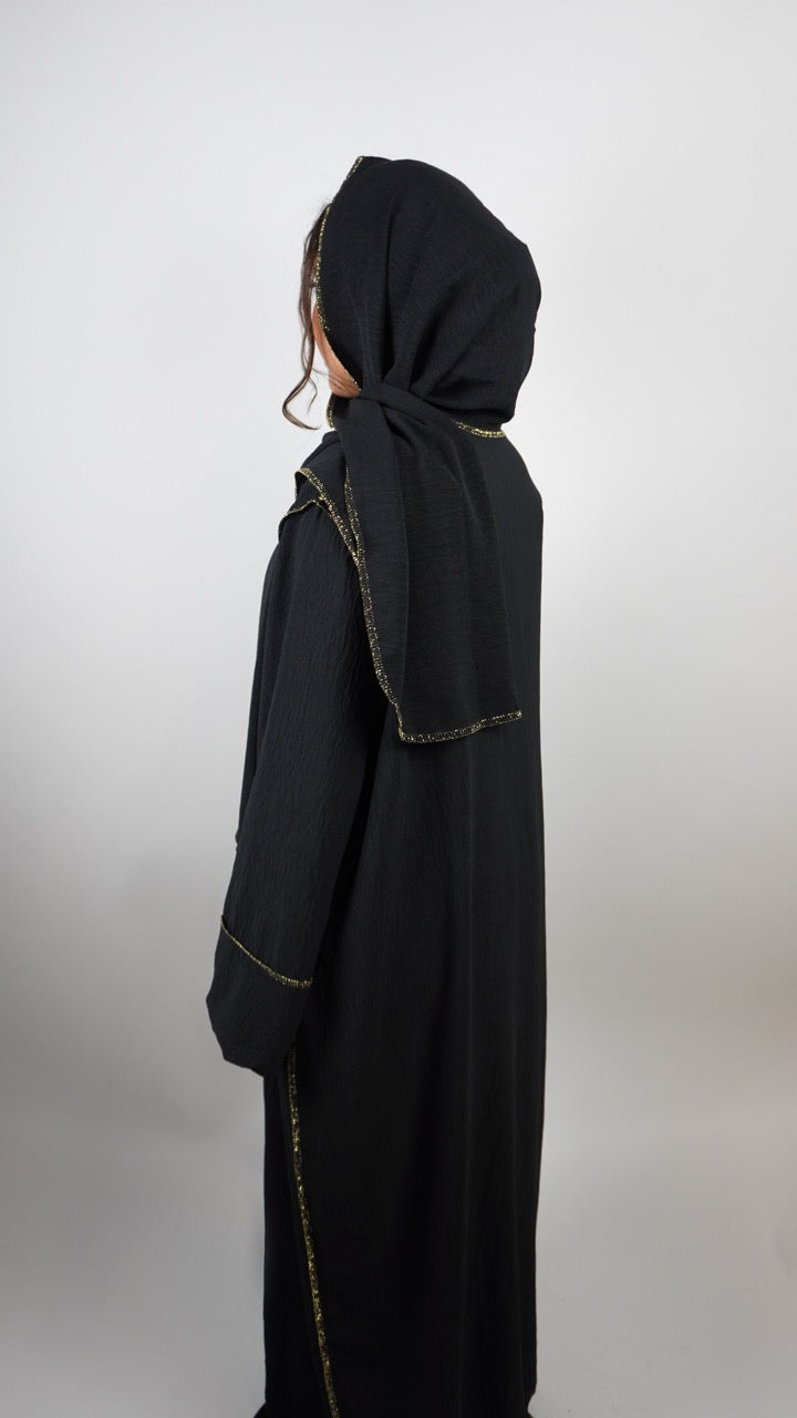 Schwarze Einteiler-Abaya aus Crêpe mit integriertem Hijab und goldener Paspel, gezeigt in Rückansicht.
