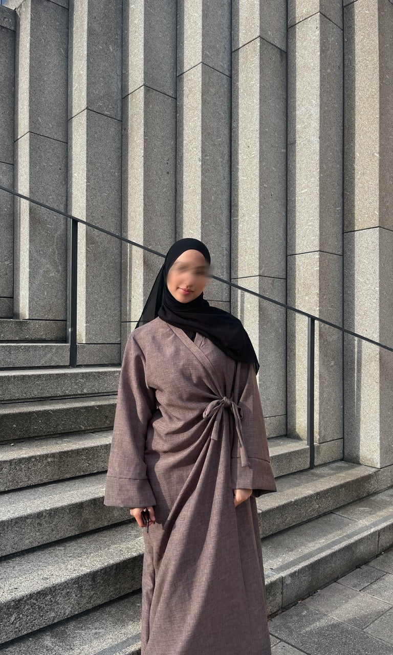 Taupefarbene Wickelabaya in Leinenoptik mit Schleifenbindung, Modest Look mit schwarzem Hijab, Vorderansicht