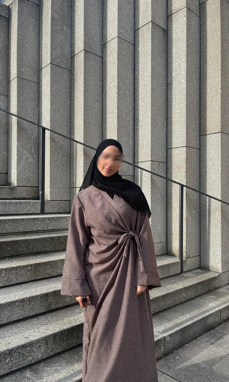 Taupefarbene Wickelabaya in Leinenoptik mit Schleifenbindung, Modest Look mit schwarzem Hijab, Vorderansicht