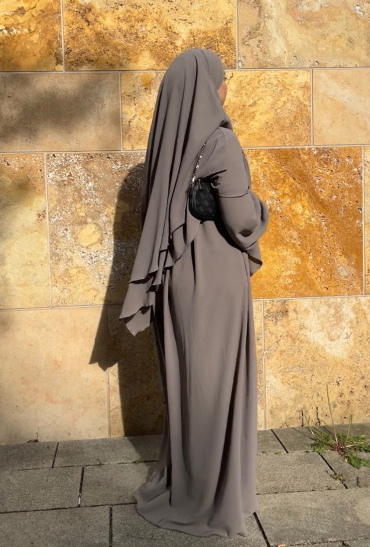 Gezeigt wird ein schwarzes, zweilagiges Khimar- und Abaya-Set aus fließendem Stoff mit Ballonärmeln in Frontalansicht.