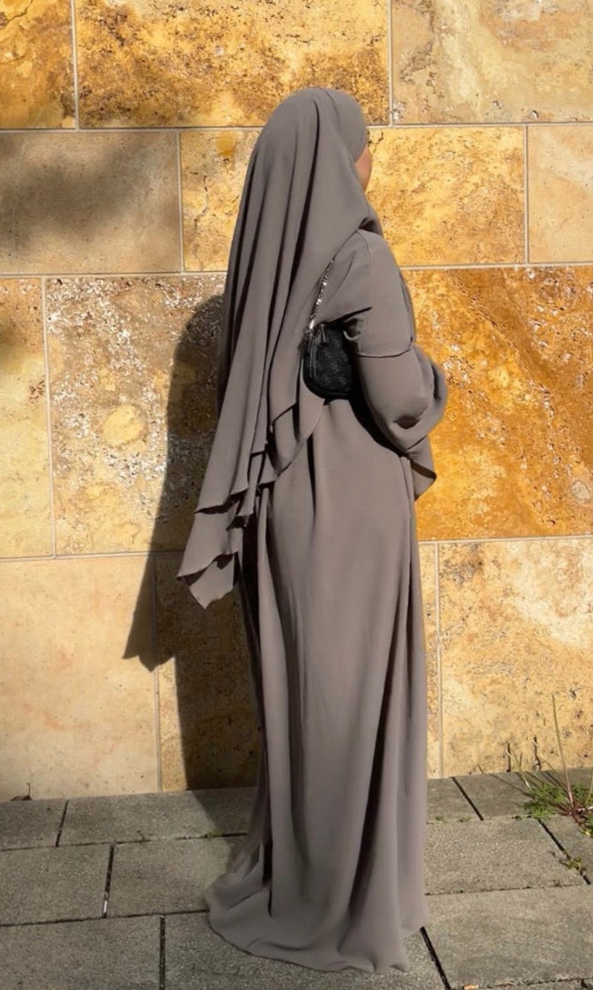 Gezeigt wird ein schwarzes, zweilagiges Khimar- und Abaya-Set aus fließendem Stoff mit Ballonärmeln in Frontalansicht.