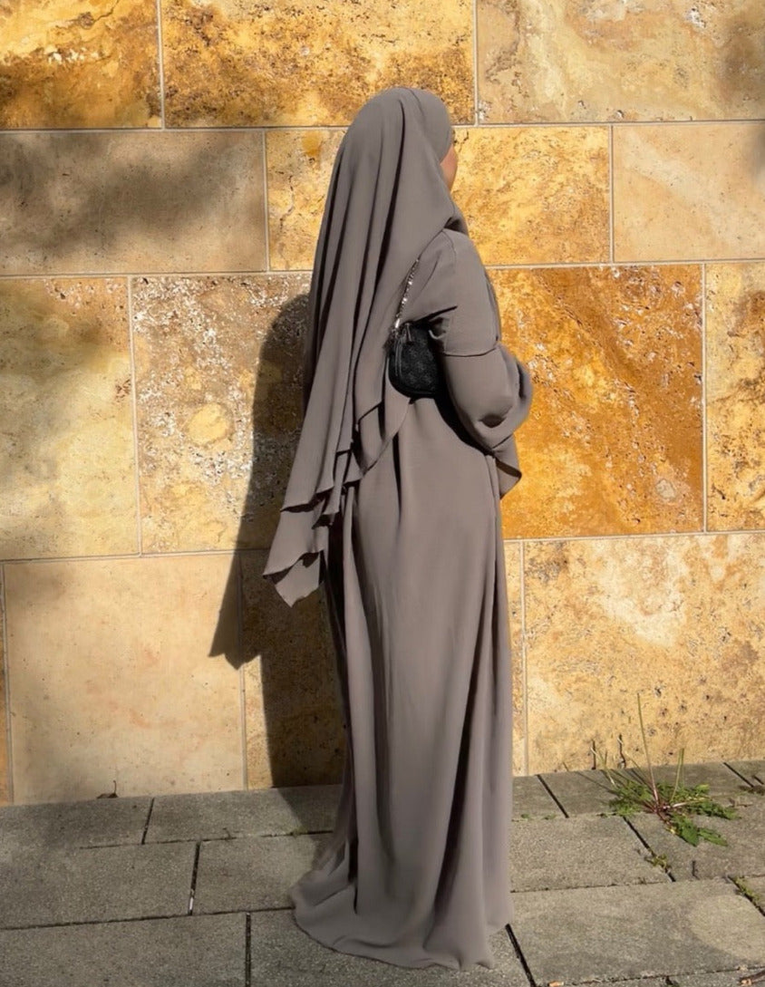 Gezeigt wird ein schwarzes, zweilagiges Khimar- und Abaya-Set aus fließendem Stoff mit Ballonärmeln in Frontalansicht.