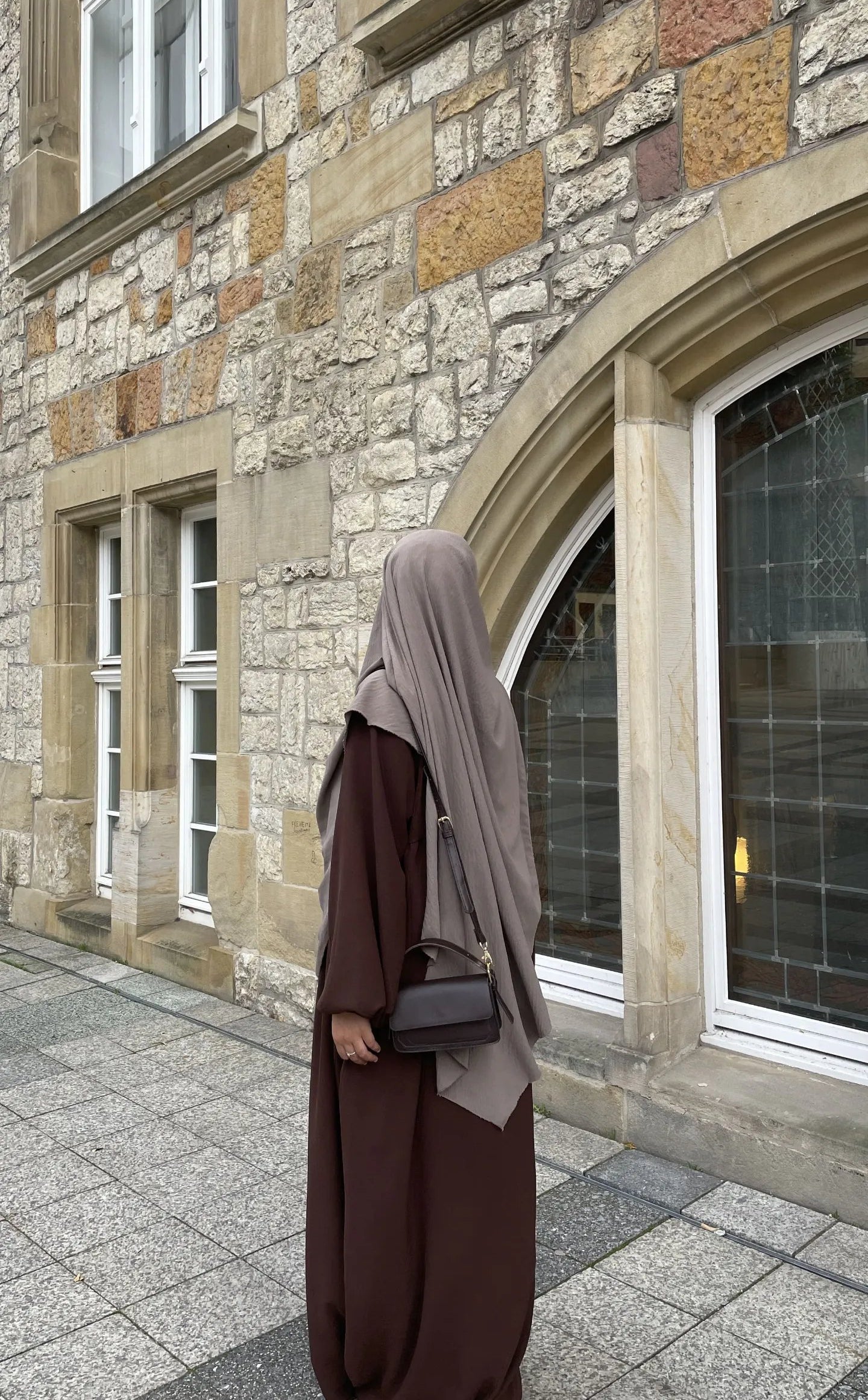 Eine braune Still-Abaya aus leichtem Jazzstoff mit Ballonärmeln ist in Frontansicht zu sehen.