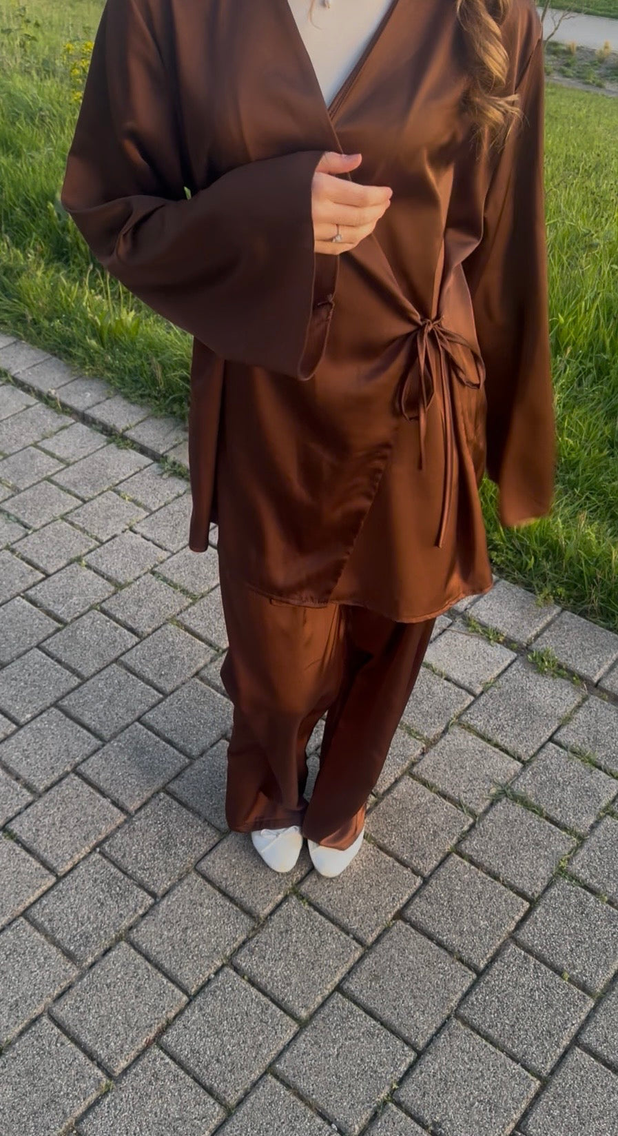 Schokobrauner Zweiteiler aus glänzendem Stoff mit Wickeloberteil zum Binden und weiter Hose, Frontalansicht.