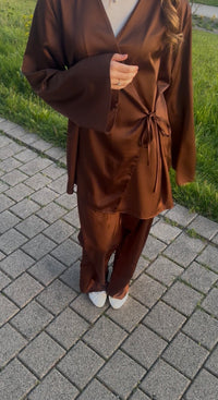 Schokobrauner Zweiteiler aus glänzendem Stoff mit Wickeloberteil zum Binden und weiter Hose, Frontalansicht.
