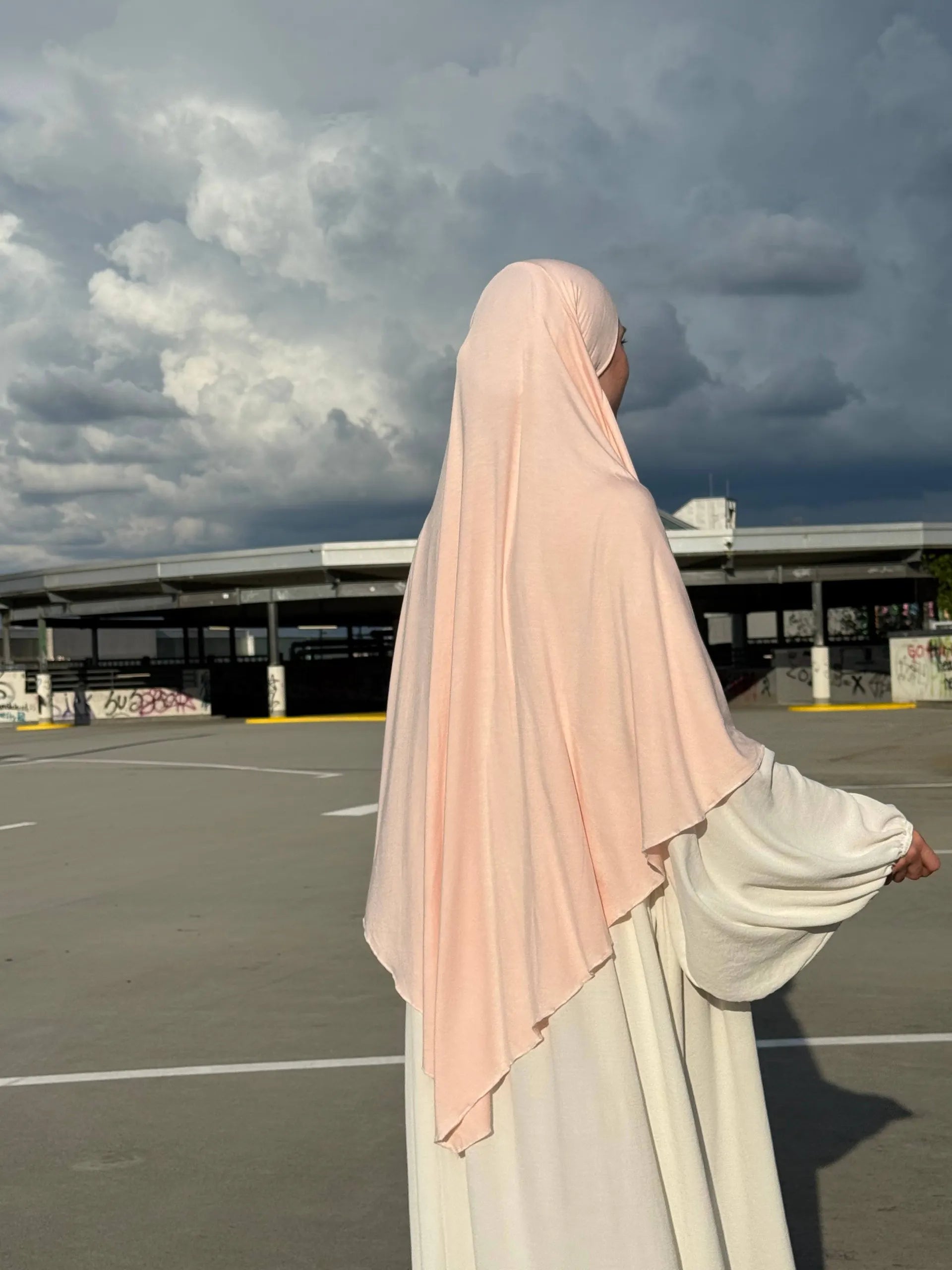 Ein Jersey Khimar in hellrosa aus Viskose-Elastan ist seitlich von hinten zu sehen.