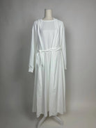 Eine weiße Open-Abaya im Dubai-Stil aus Medina-Seide mit Unterkleid und Bindegürtel wird in Vorderansicht gezeigt.