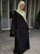 schwarzer zweiteiler mit weitem oberteil, glockenärmeln und langem maxirock, frontansicht