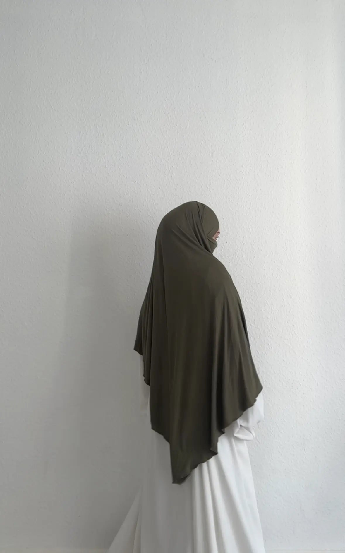 Jersey Khimar in Olivgrün aus Viskose-Elastan, seitliche Rückansicht mit Gesicht im Profil.