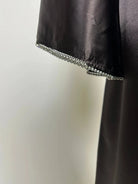 Schwarze Abaya aus satinartigem Polyester mit Strassbesatz am Ärmelsaum, Detailaufnahme