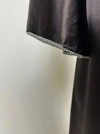 Schwarze Abaya aus satinartigem Polyester mit Strassbesatz am Ärmelsaum, Detailaufnahme