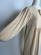 Beiges Musselin-Kleid aus Baumwolle mit weitem langem Ärmel und rundem Ausschnitt mit Bindeband, Detailaufnahme seitlich
