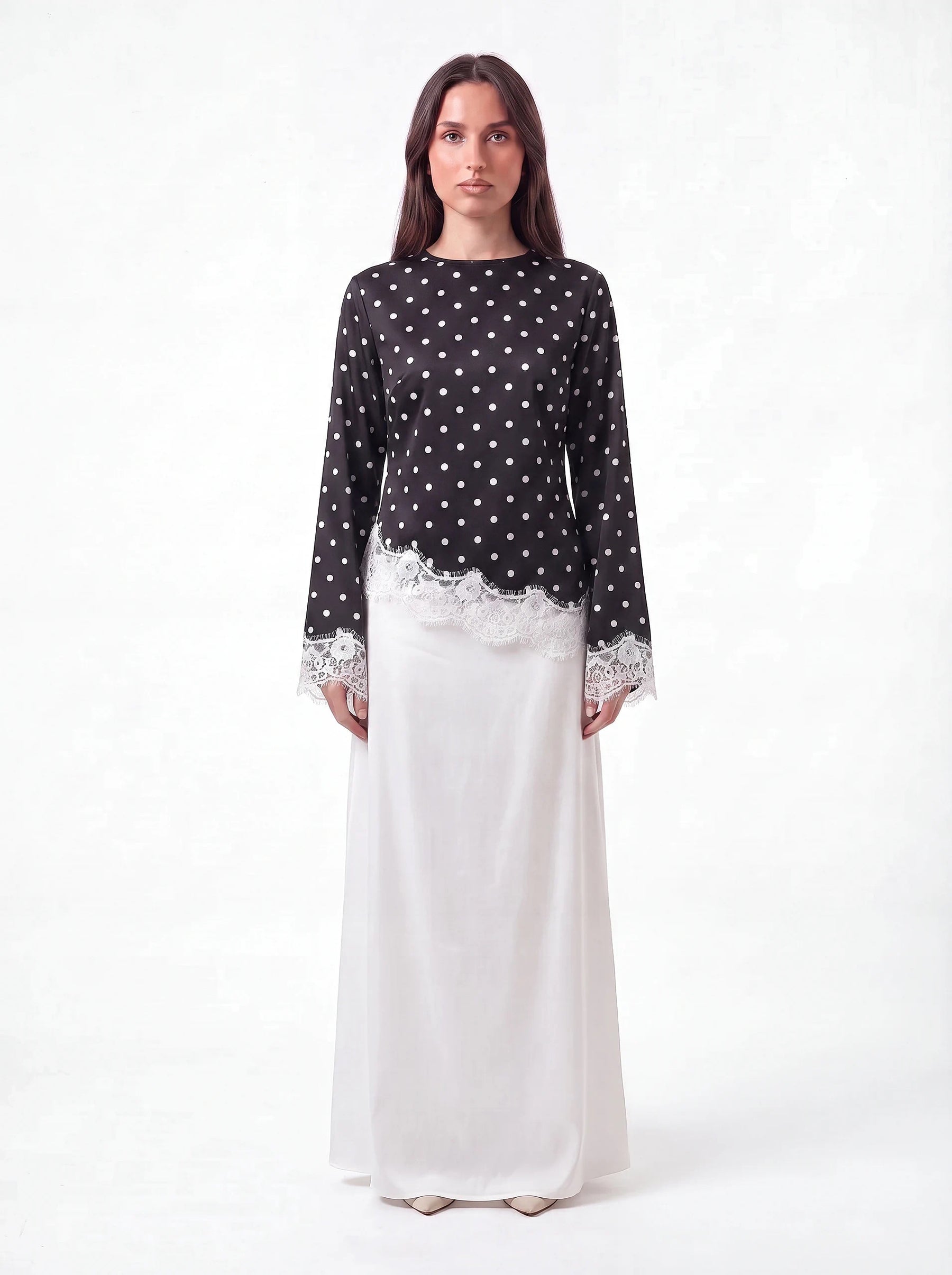 Oberteil in Schwarz mit weißen Polka Dots und Spitzenbesatz am Saum, Frontalansicht.
