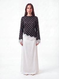 Oberteil in Schwarz mit weißen Polka Dots und Spitzenbesatz am Saum, Frontalansicht.
