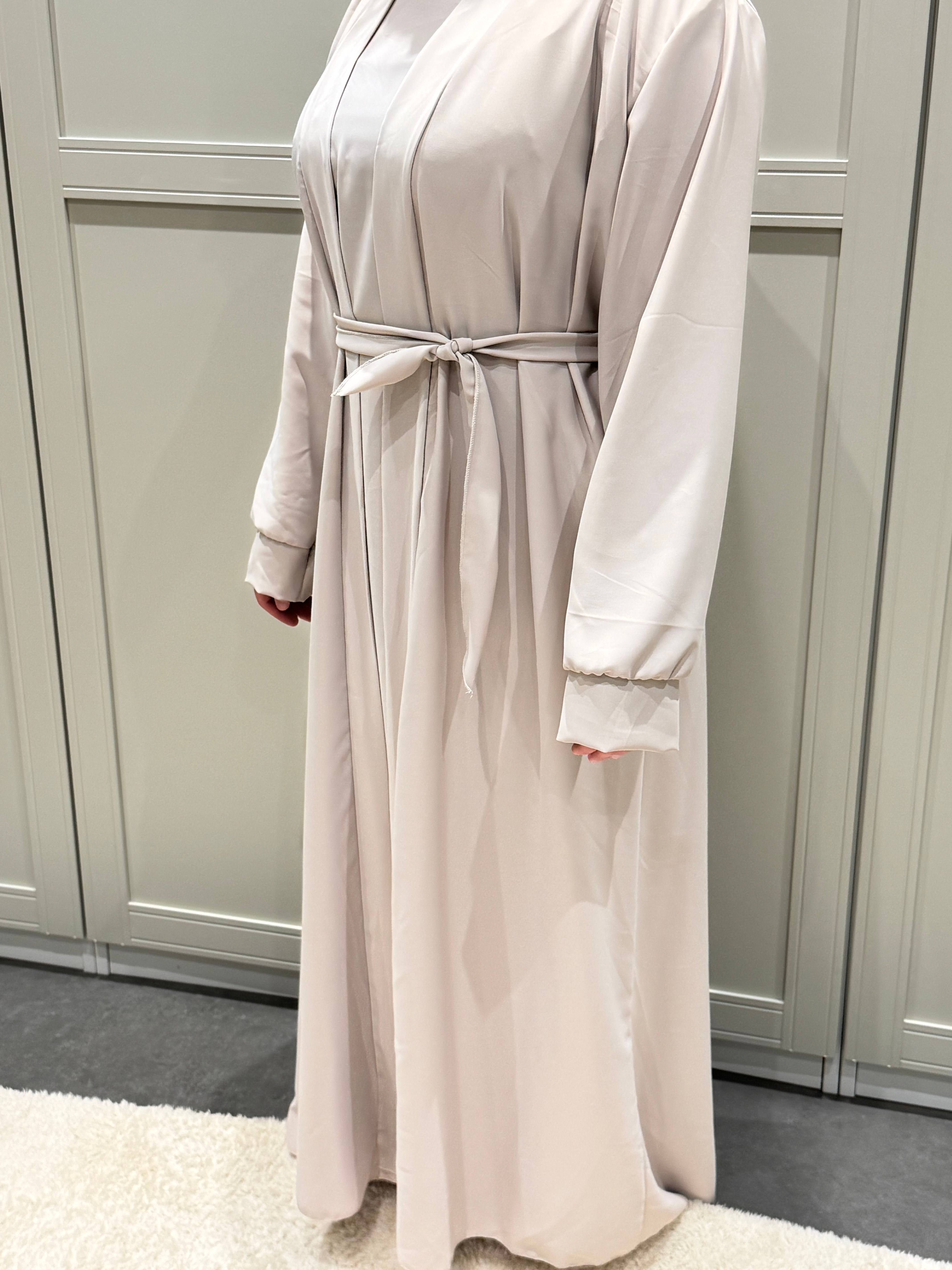 Zu sehen ist eine cremefarbene Open-Abaya aus seidigem Stoff mit Bindegürtel und weiten Ärmeln, Vorderansicht.