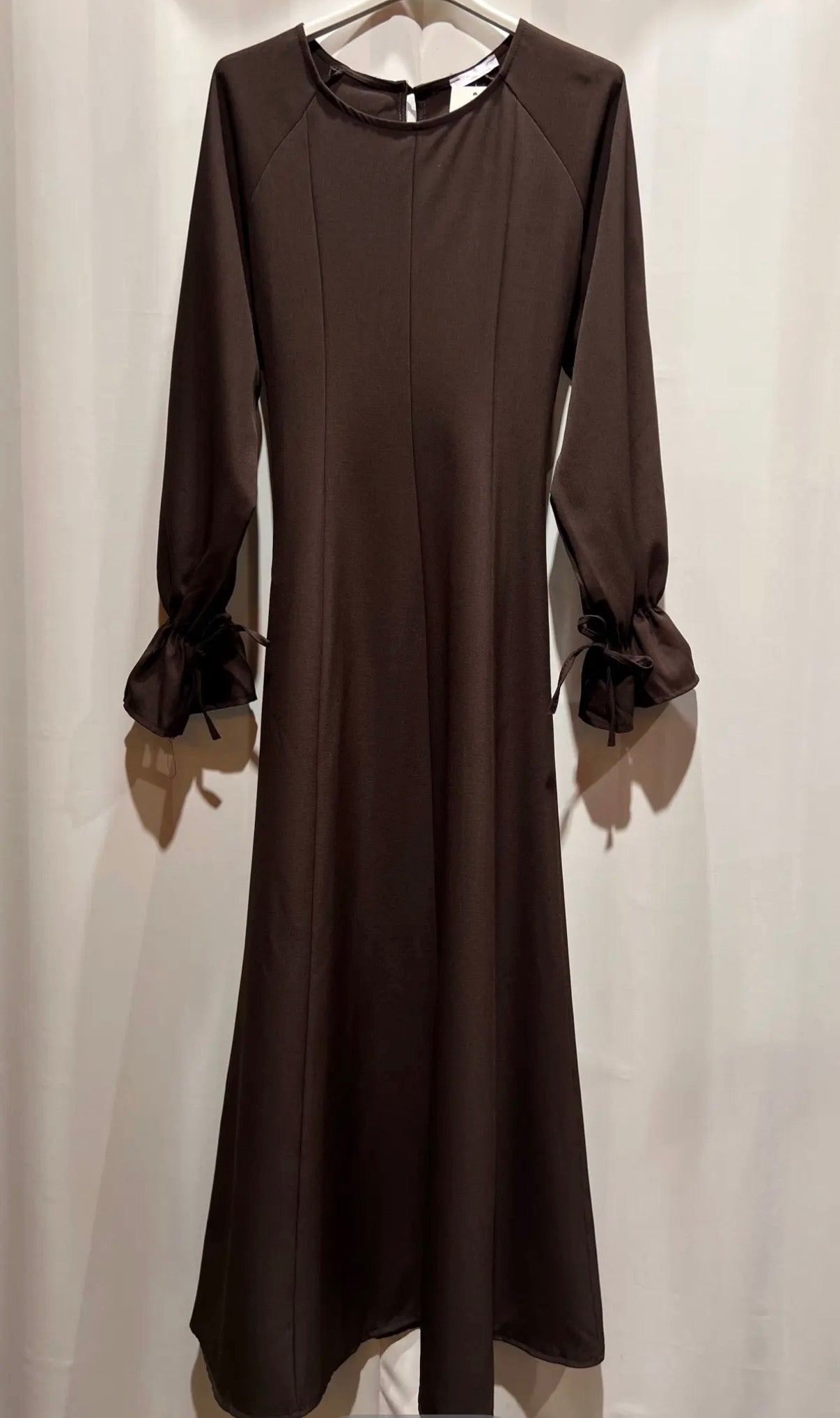 Dunkelbraunes Kleid in A-Linie mit Rundhalsausschnitt und dekorativen Schnürungen an den Ärmeln, Frontalansicht.