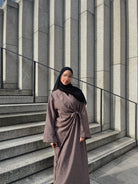 Taupefarbene Wickelabaya in Leinenoptik mit Schleifenbindung, Modest Look mit schwarzem Hijab, Vorderansicht