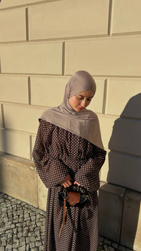Kleid in braun mit weißem Punktemuster und weiten Ärmeln, kombiniert mit taupefarbenem Hijab.