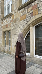 Eine braune Still-Abaya aus leichtem Jazzstoff mit Ballonärmeln ist in Frontansicht zu sehen.