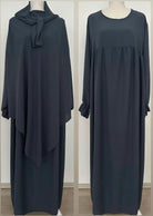 Abaya und Khimar in anthrazit; Khimar lang, gebunden vorn, Abaya mit geraffter Brust und Rüschenärmeln, Frontansicht.