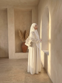 Weiße Abaya aus luftigem Stoff mit Rüschenärmeln wird in Seitenansicht gezeigt