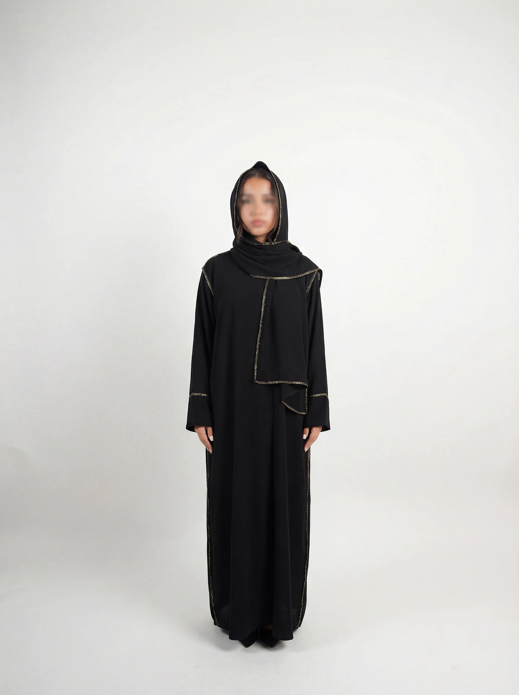 Schwarze Einteiler-Abaya aus strukturiertem Stoff mit integriertem Hijab und goldener Paspel, Dreiviertelansicht.