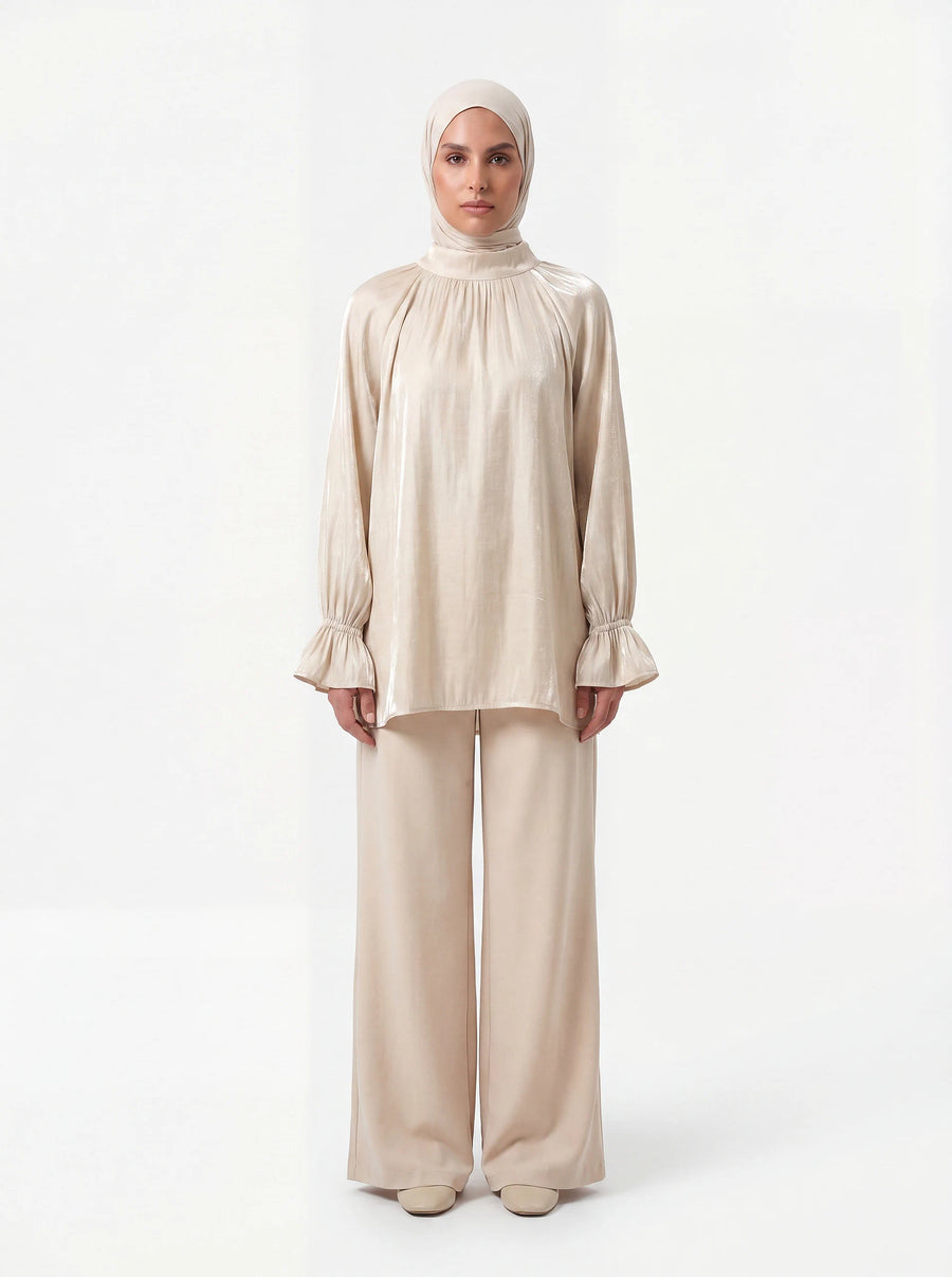 Champagnerfarbene Bluse aus glänzendem Stoff mit gerafftem Kragen und Volant-Ärmeln, Frontalansicht.
