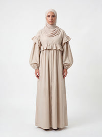Sandfarbenes Kleid mit Rüschen an Brust und Schultern sowie weiten Ballonärmeln, Frontalansicht.