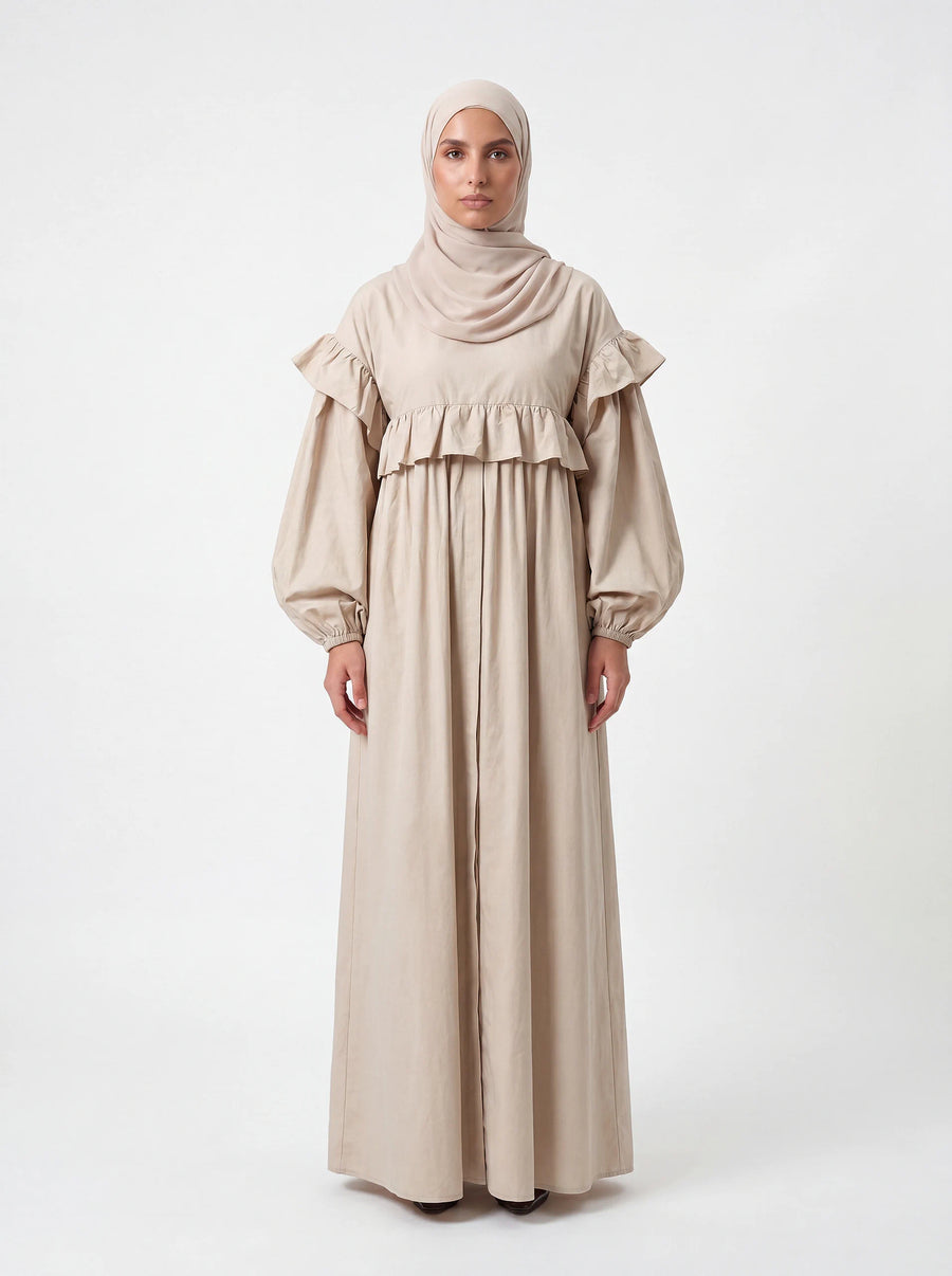 Sandfarbenes Kleid mit Rüschen an Brust und Schultern sowie weiten Ballonärmeln, Frontalansicht.