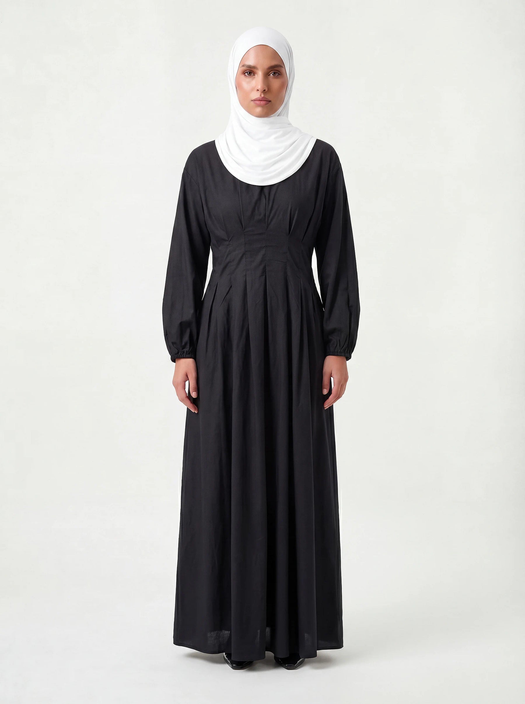 Schwarzes Maxikleid mit vertikaler Faltenlegung im Taillenbereich und elastischen Ärmelbündchen, Frontalansicht.