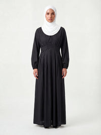 Schwarzes Maxikleid mit vertikaler Faltenlegung im Taillenbereich und elastischen Ärmelbündchen, Frontalansicht.