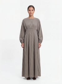 Bodenlanges Kleid in Taupe mit Taillenfalten, langen Ärmeln und Rundhalsausschnitt in Frontalansicht.
