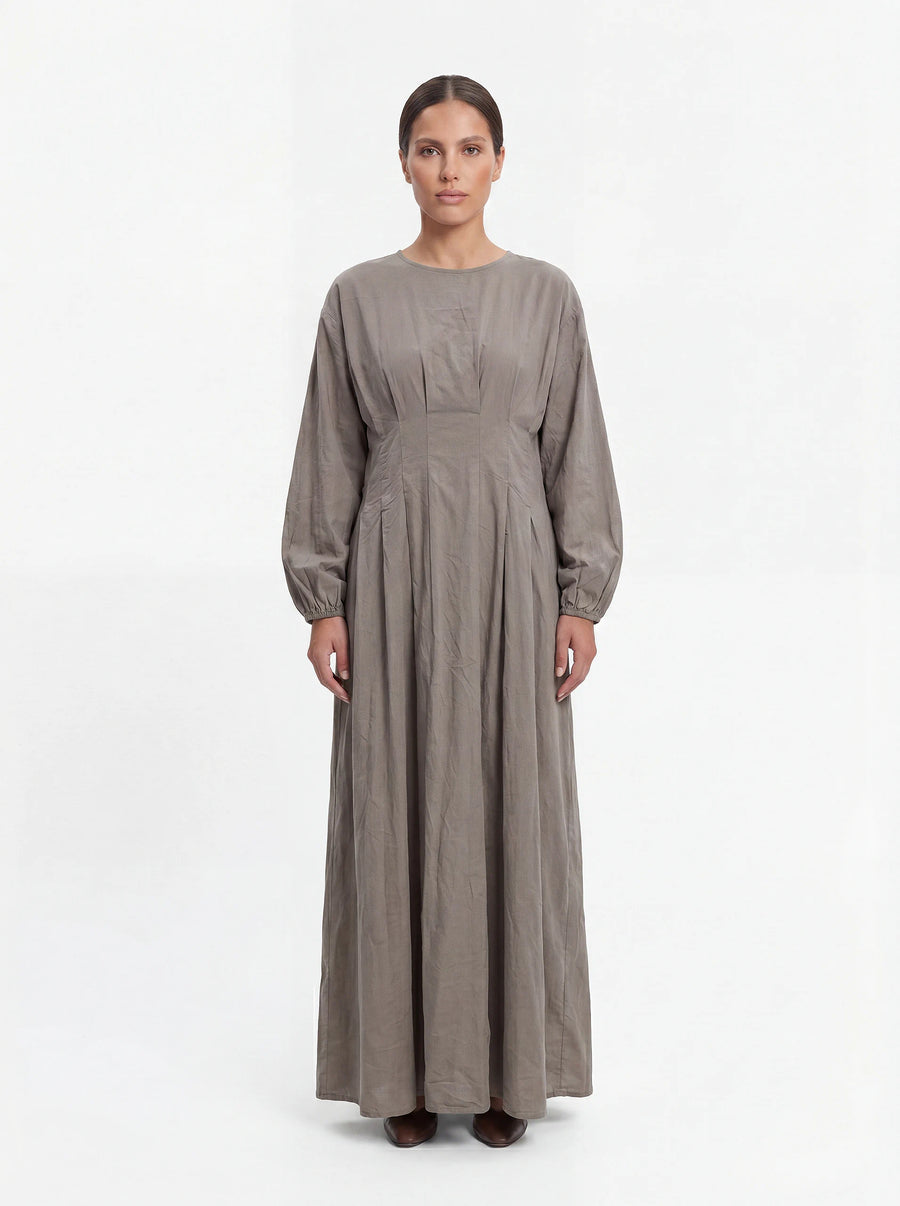 Bodenlanges Kleid in Taupe mit Taillenfalten, langen Ärmeln und Rundhalsausschnitt in Frontalansicht.