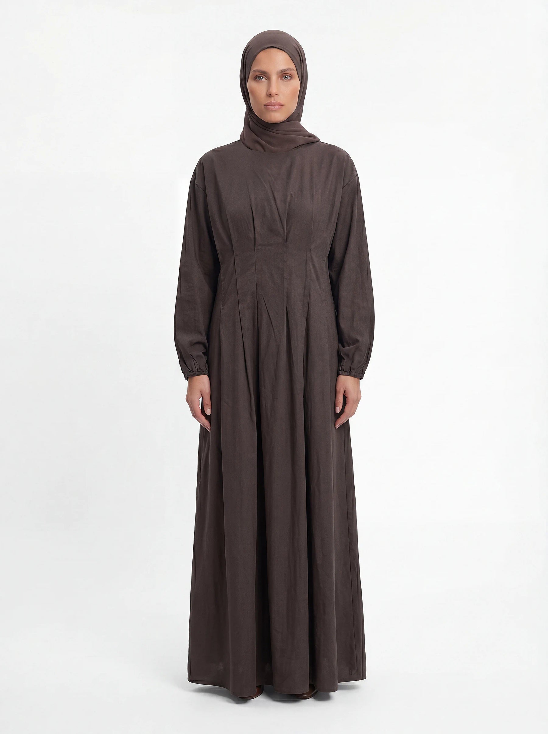 Bodenlanges Kleid in Dunkelbraun mit Faltenlegung im Taillenbereich und passendem Hijab, Frontalansicht.