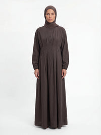 Bodenlanges Kleid in Dunkelbraun mit Faltenlegung im Taillenbereich und passendem Hijab, Frontalansicht.