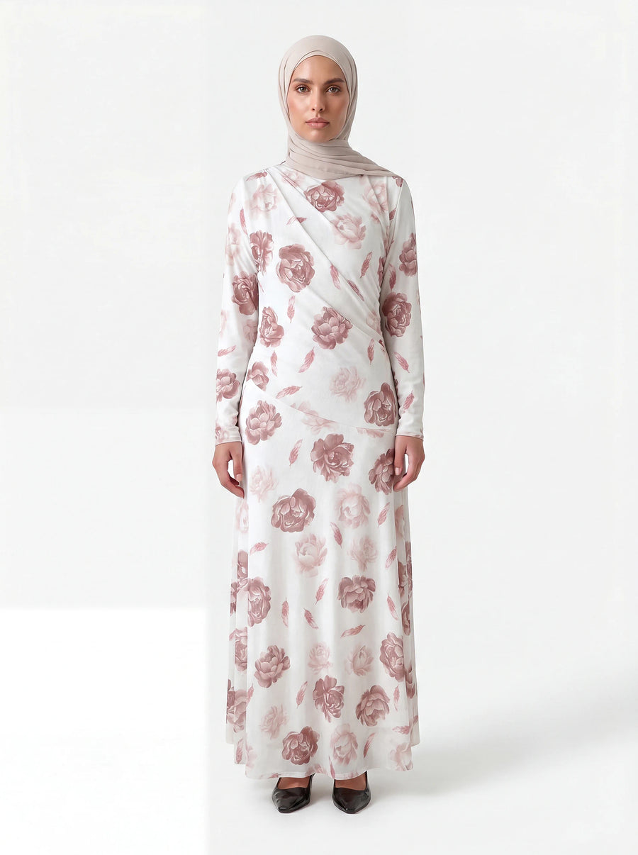 Weißes langärmliges Kleid mit altrosa Blütenmuster, Wickeldetail am Oberkörper und fließendem Rock, Frontalansicht.