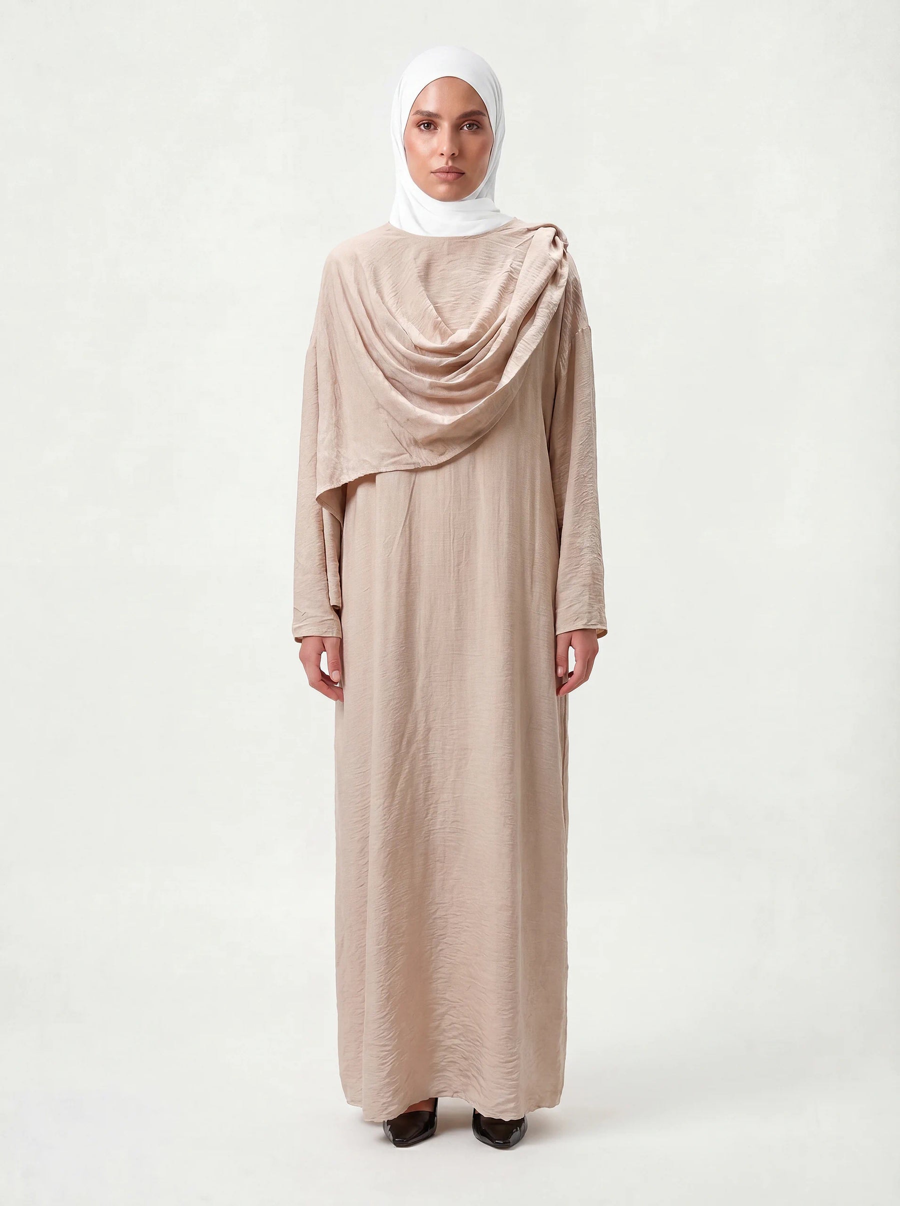Bodenlanges Cape-Kleid in Sandbeige mit drapiertem Brustdetail und langen Ärmeln, Frontalansicht.