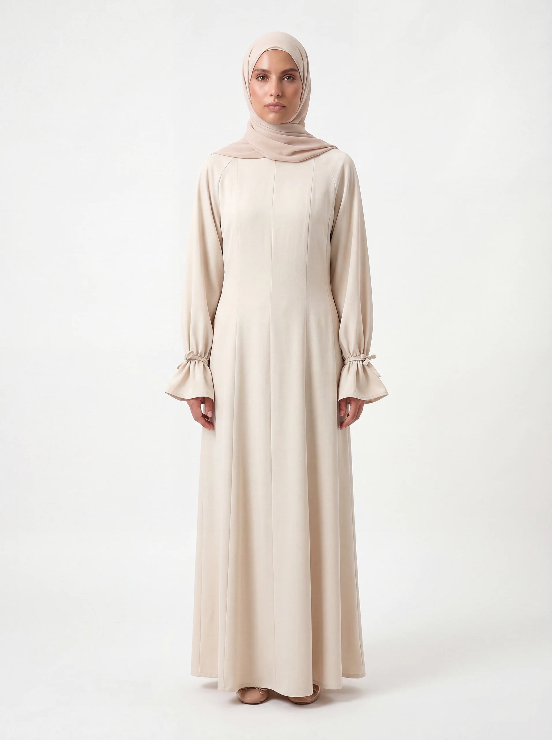 Bodenlanges cremefarbenes Kleid mit gerafften Ärmelabschlüssen und vertikalen Teilungsnähten, Frontalansicht.