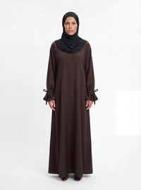 Dunkelbraunes Maxikleid mit gerafften Ärmelabschlüssen und dekorativen Schleifen, Frontalansicht.