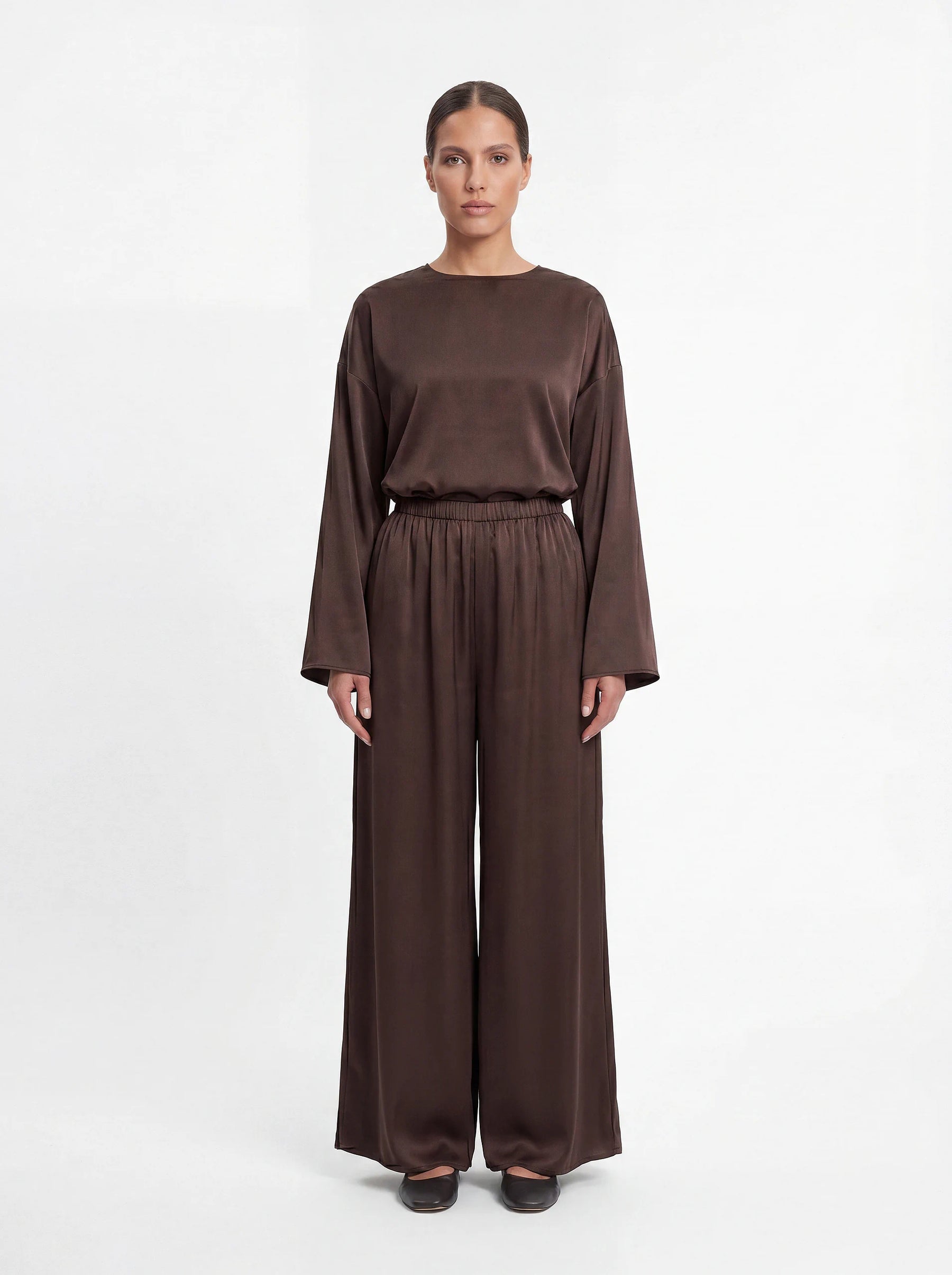 Schokoladenbraune Wide-Leg-Hose aus glänzendem, fließendem Stoff mit elastischem Bund, Frontalansicht.