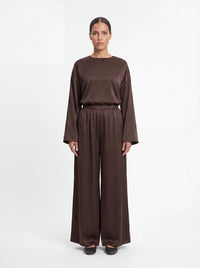 Schokoladenbraune Wide-Leg-Hose aus glänzendem, fließendem Stoff mit elastischem Bund, Frontalansicht.
