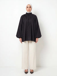 Schwarze Bluse mit Stehkragen, gerafften Ballonärmeln und weitem A-Linien-Schnitt, Frontalansicht.