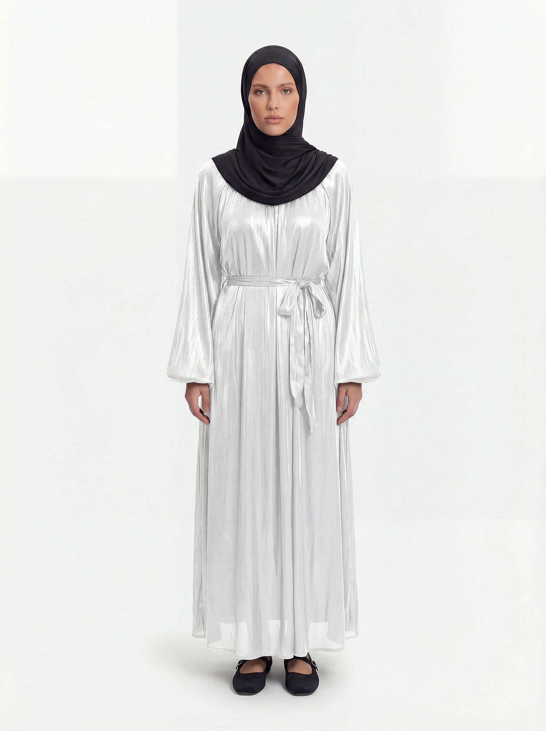 Perlweiß glänzende Abaya mit weiten Ballonärmeln und passendem Bindegürtel in der Frontalansicht.