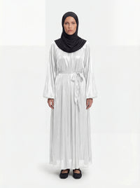 Perlweiß glänzende Abaya mit weiten Ballonärmeln und passendem Bindegürtel in der Frontalansicht.