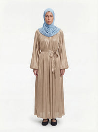 Champagnerfarbene Abaya aus glänzendem Stoff mit Ballonärmeln und Bindegürtel, Frontalansicht mit hellblauem Hijab.